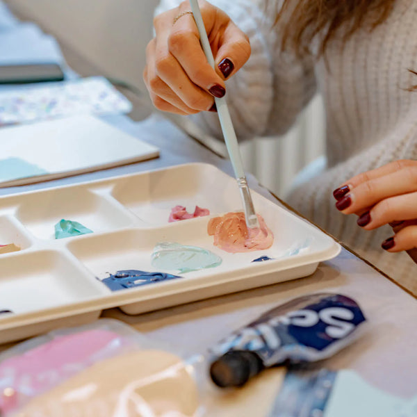 Person painting with a brush on a palette with Sculpd canvas painting kits