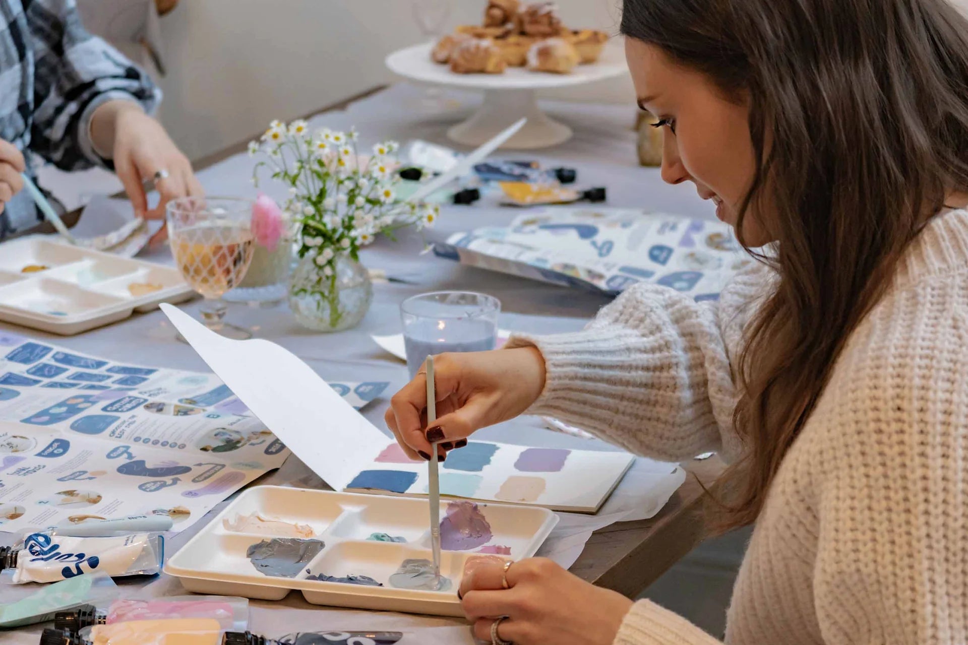 Woman painting at a table with art supplies