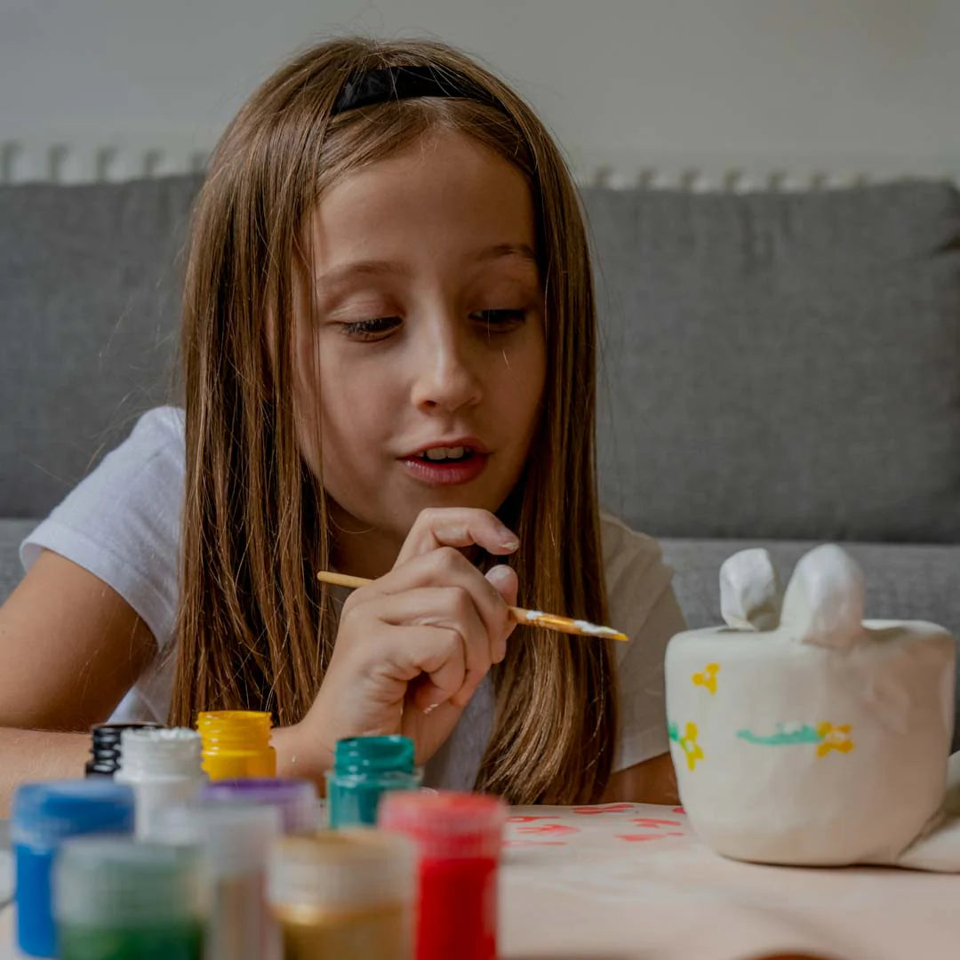 A young girl painting her sculpted clay with Sculpd kids craft bundle kit