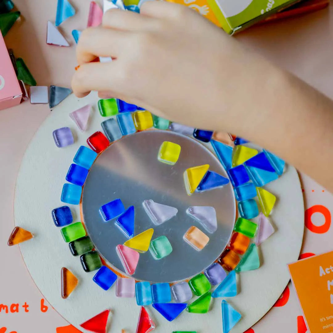 Child's placing mosaic tiles on mirror