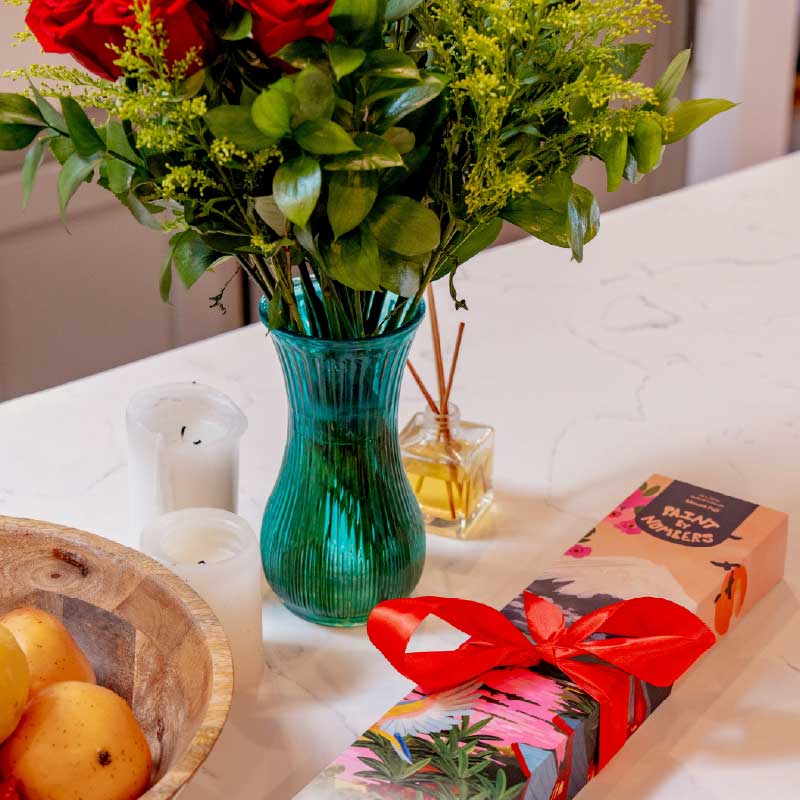Bouquet of red roses in a blue vase on a table with paint by numbers gift kit